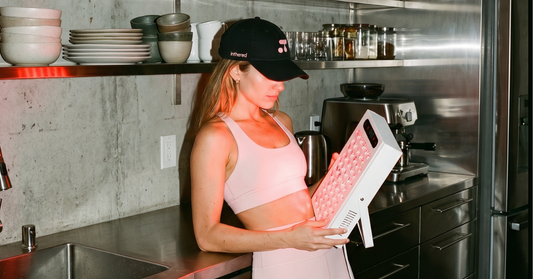 Lady in a pink outfit using an ITR-EVO red light therapy panel